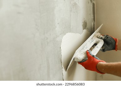 Worker plastering walls with gypsum plaster and spatula . Construction of house and home renovation concept. Close up of stucco and handyman hands with trowel