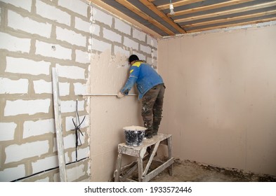 A Worker Plasters The Walls In The Room. Building A House