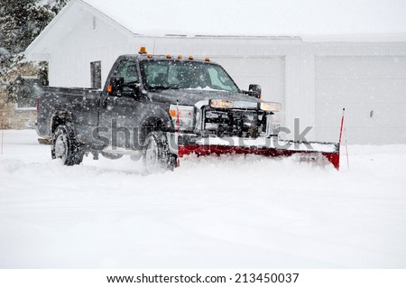 a worker plows heavy white snow during a Michigan winter