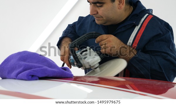 Worker polish a car with auto polisher. Close\
up of worker hands using an auto polisher to polish the car body in\
the workshop\
