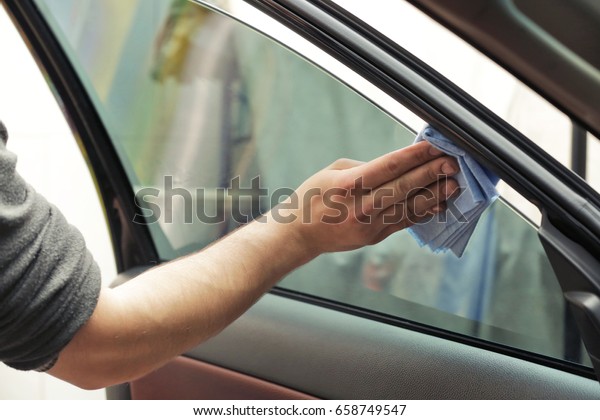 Worker polishing tinted car\
window