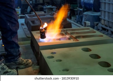 The worker is preheating to mold for casting.  Sand casting, also known as sand molded casting, is a metal casting process characterized by using sand as the mold material. - Powered by Shutterstock