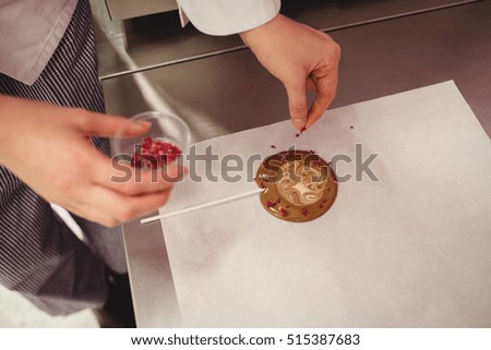 Worker preparing lollipop on wax paper in kitchen