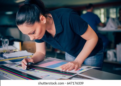Worker in a printing and press centar uses a magnifying glass and check the print quality - Shutterstock ID 647176339