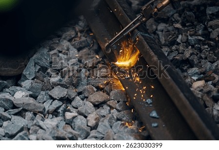 A worker in the process of a railroad track weld repair, reconstruction with a freight train passing