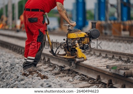 A worker in the process of a railroad track weld repair, reconstruction with a freight train passing