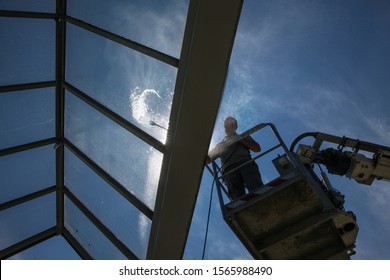 worker of Professional Facade Cleaning Services washing a galss roof