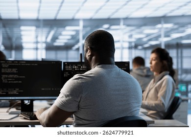 Worker programming in server room housing advanced equipment storing massive datasets. Technician typing code on PC to mend data center racks doing complex computational operations