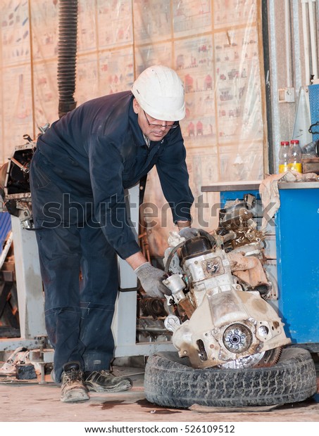worker in protective clothes repairs the\
automobile mechanism