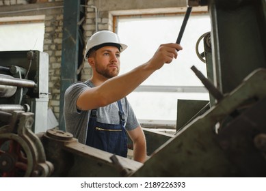 Worker In Protective Clothing In Factory Using Machine.