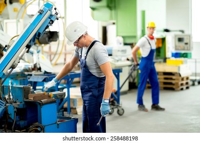 Worker In Protective Clothing In Factory Using Machine