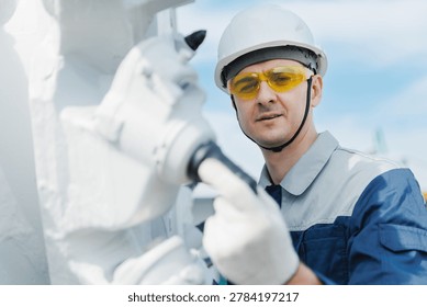 Worker in protective gear examining mining equipment, milling machine.