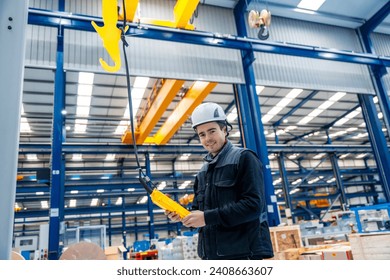 Worker with protective hard hat controlling an industrial crane with control remote - Powered by Shutterstock