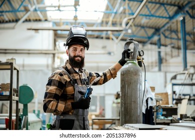 A worker with a protective mask on his head is preparing to do some welding works in his workshop. Worker with a welding machine.