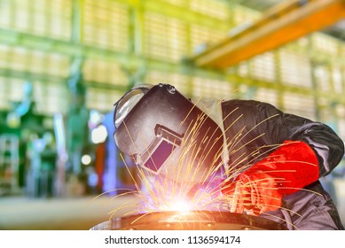 worker with protective mask welding metal process at factory by Mig welder machine, sparks bright 