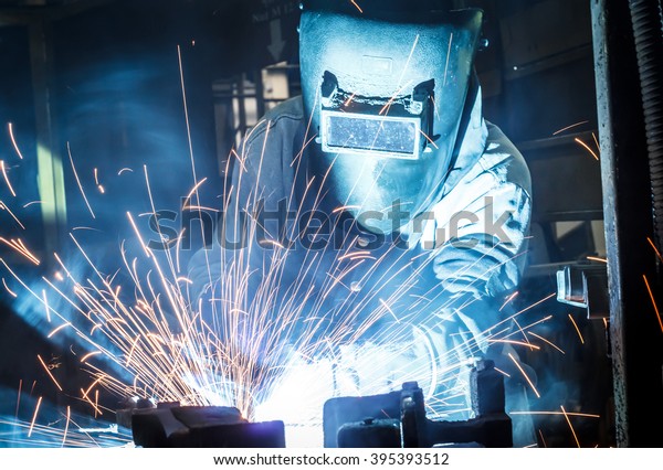 worker with protective\
mask welding metal