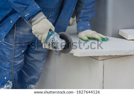a worker in a protective suit treats a stone with a power tool