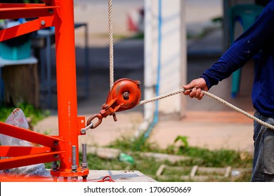 Worker Pulling Rope By Fixed Pulley At Construction Site.