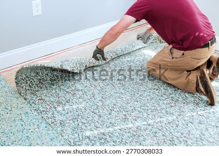 Worker pulls up piece of old carpet in room with light walls wood floor.