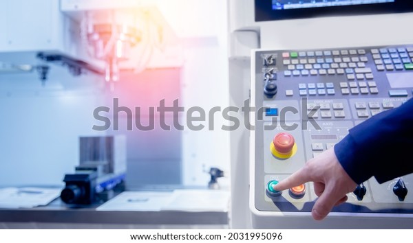 Worker push start control panel\
of CNC machine at factory floor to get metal detail\
production.