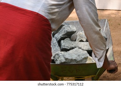 Worker Pushing Trolley Full Of Big Black Rocks Or Stones To Build Foundation, Boundary Wall At A Construction Site Kerala, India. Used For Building A House Or Villa Or Apartment, Bridge, Roadways.