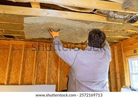 Worker puts insulation panels in ceiling of house during home improvement project, showcasing renovation efforts.