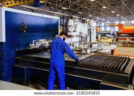 Worker puts steel sheet into loading unit of cutting machine.