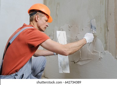 Worker Is Putting A Gypsum Plaster On A Wall. He Is Using  Trowels.