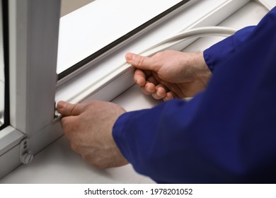 Worker putting rubber draught strip onto window indoors, closeup - Shutterstock ID 1978201052