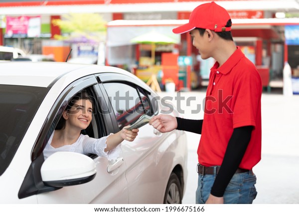 worker receiving money from driver customer\
after refueling a vehicle at gas\
station
