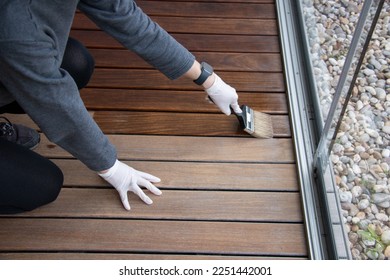 Worker refinishing wood, hand painting wooden deck floor with wood protection oil - Shutterstock ID 2251442001