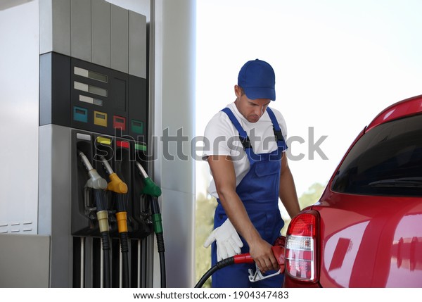Worker refueling car\
at modern gas station