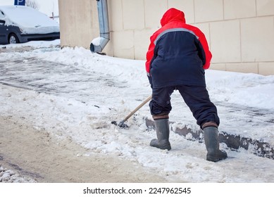 Worker remove ice and clear snow from paving slabs using an icebreaker. Man breaks ice with steel blade crusher, handle ice-breaking tool. The janitor clean up area.