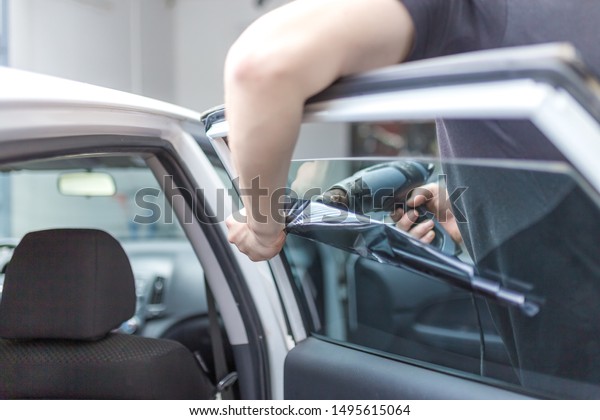 Worker removing car window film foil by using hot
air gun.