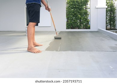 Worker and renovation work. To using roller painting mortar cement or finishing material for repair crack, skim coat or improvement surface of concrete pavement floor or slab for driveway or garage.