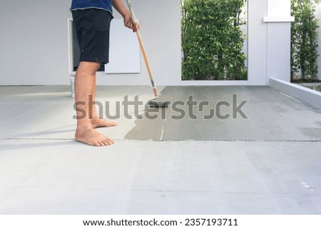 Worker and renovation work. To using roller painting mortar cement or finishing material for repair crack, skim coat or improvement surface of concrete pavement floor or slab for driveway or garage.