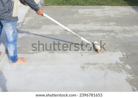 Worker and renovation work. To using roller painting mortar cement or finishing material for repair crack, skim coat or improvement surface of concrete pavement floor or slab for driveway or garage.