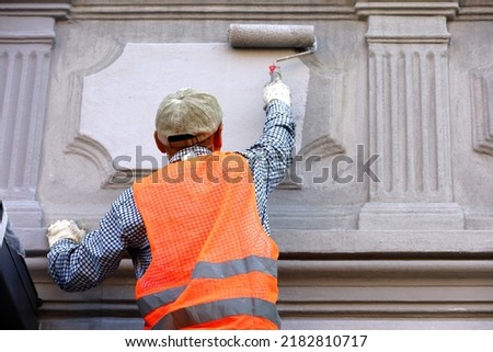 Worker repair the building wall. Builder painting the facade, construction and repair works