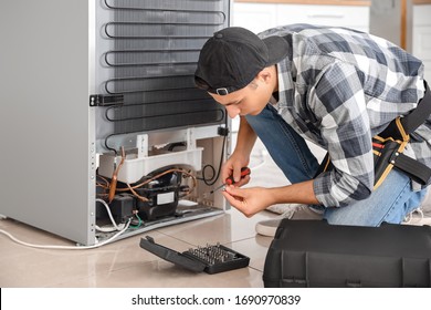Worker repairing refrigerator in kitchen