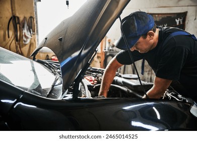 Worker, repairman wearing cap, repairing car engine. Hardworking man opening car hood, looking, working in garage, auto, servicing center. Concept of manual labor. - Powered by Shutterstock