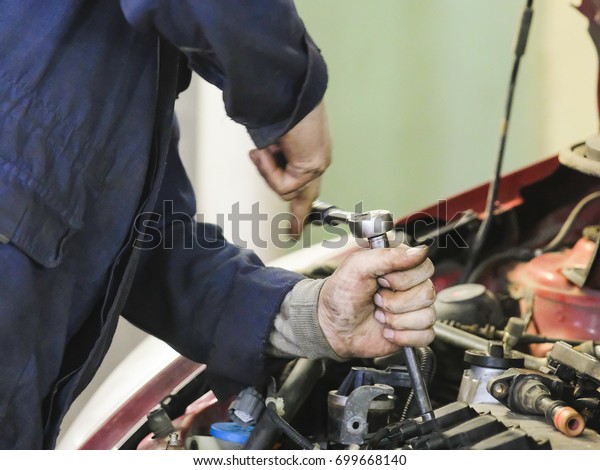 Worker repairs a\
car in a car repair\
station