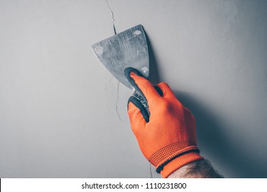 Worker repairs a crack in the wall from shrinkage of the building or poor-quality work