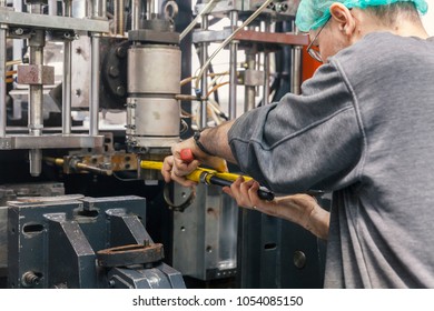 worker repairs a machine for plastic injection, close up