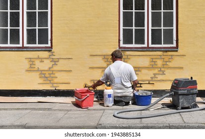 A Worker Restores A Brick Facade Of A Building 