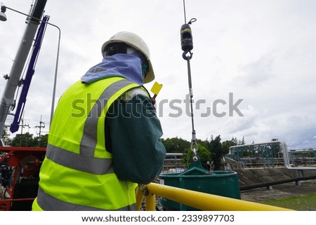 Worker or rigger during lifting deformed bars by using hand signal which meant crane is up in construction chemical site.  