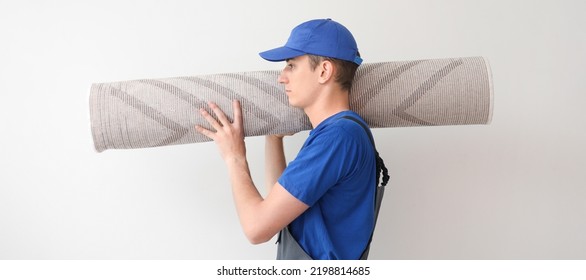 Worker with rolled carpet on light background - Powered by Shutterstock