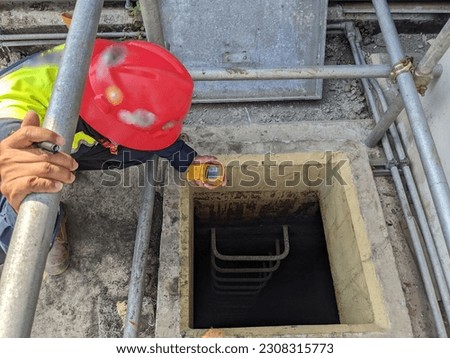 Worker and safety officer take data for gas test before confine space activity. The photo is suitable to use for industrial background and construction content media.