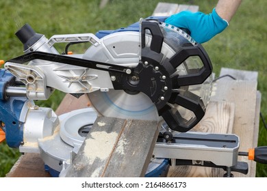 The worker saws the boards. Sawmill. timber harvesting process. Miter saw for cutting wood at work. Tool for carpentry. A man works with a tool. Partial view of joiner's boards with miter saw. 