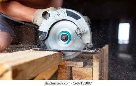 A worker saws a wooden beam. Building a house. - Powered by Shutterstock