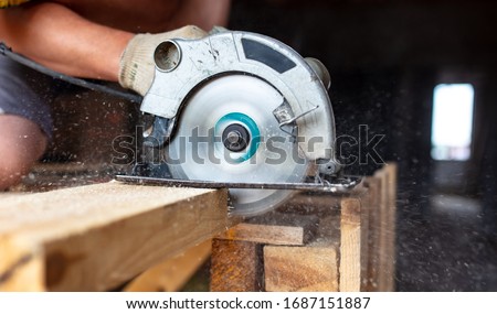 A worker saws a wooden beam. Building a house.